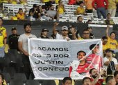 Hinchas con un cartel que prometieron llevar en los demás partidos en homenaje a Justin Cornejo.