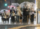 Tokio. Varias personas tratan de protegerse de la lluvia.