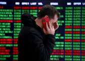 Una persona habla por teléfono frente a los paneles indicadores en la Bolsa de Valores de Australia (ASX) en Sídney, Australia.