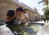 Unos turistas se refrescan en una fuente del Patio de los Naranjos de la Mezquita Catedral de Córdoba (España).