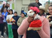 Una mujer muestra su mascota, vestida con el ropaje propio de su comunidad indígena andina.
