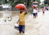 La gente camina entre el agua estancada en una vía en Amarpur Agartala, estado de Tripura, noreste de la India.