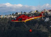 Fotografía de un helicóptero de bomberos lanzando agua para extinguir un incendio el 12 de septiembre de 2024 en las laderas del cerro El Panecillo, ubicado en el centro Histórico de Quito (Ecuador).