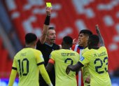 Jugadores de Ecuador discuten con el árbitro Raphael Claus una tarjeta amarilla para Pervis Estupiñán (c) en el partido Ecuador vs Paraguay