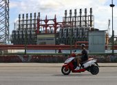 Un hombre en una moto eléctrica pasa frente a una de las plantas de generación eléctrica que permanece este domingo 20 de octubre, en el puerto de La Habana (Cuba).