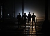 personas caminan por una calle durante un apagón este domingo, en La Habana (Cuba).