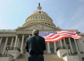 Un hombre con una bandera de los Estados Unidos delante del Capitolio en Washington.