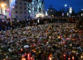 Los dolientes se ubican alrededor de monumento improvisado con flores y velas para las víctimas de un ataque con coche en un mercado navideño en Magdeburgo.