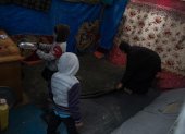 Una mujer palestina desplazada internamente limpia su tienda con sus hijos.