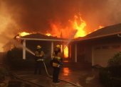 Bomberos combatiendo un incendio que envuelve una vivienda en Palisades, Los Ángeles.