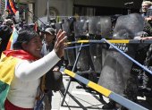 Una partidaria del expresidente Evo Morales, hace un gesto frente a agentes de la policía antidisturbios durante la marcha "Comunales por la Vida" contra el gobierno de Luis Arce
