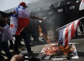 Personas queman una bandera de Estados Unidos durante una protesta por la visita del Secretario de Estado de Estados Unidos, Marco Rubio.