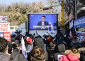 Los partidarios miran imágenes de archivo de los discursos del líder surcoreano Yoon Suk Yeol (C) en una pantalla cerca del Tribunal del Distrito Central en Seúl el 20 de febrero de 2025.