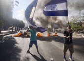 Simpatizantes del Partido Nacional de Honduras ondean banderas y queman llantas en una calle exigiendo que lleguen urnas de votación a su barrio, este domingo en Tegucigalpa (Honduras).