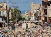 decenas de personas al caminar por una calle en ruinas y llena de basura cerca al Palacio Nacional, en Puerto Príncipe (Haití).