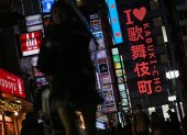 Personas caminando por una calle junto al letrero de neón "I love Kabukicho" en la zona de entretenimiento del distrito rojo