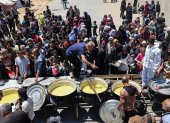 Palestinos desplazados hacen cola para recibir una porción de comida caliente en un comedor benéfico en el campo de refugiados de Nuseirat, en el centro de la Franja de Gaza, el 5 de mayo de 2025.