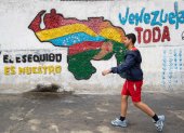 Fotografía del 2 de abril del 2025 de una persona caminando frente a un mural con el mapa de Venezuela en Caracas (Venezuela).