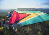 hombres desplegando una bandera de Guyana en la montaña Pakrampa, en la aldea de Arau, región Esequibo (Guyana).