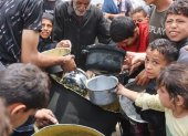Palestinos buscan conseguir un poco de comida para calmar el hambre.