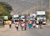 Personas caminan por una carretera tras un bloqueo realizado por seguidores del exmandatario Evo Morales este lunes, en Sipe Sipe en la región de Cochabamba (Bolivia).