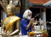 Una mujer usando mascarilla durante una visita a un sitio budista en Bangkok, Tailandia.