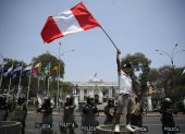 Fotografía de un hombre al ondear una bandera peruana, frente a la sede del Congreso Nacional de Perú, en Lima (Perú).