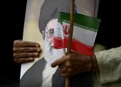Un musulmán chiita pakistaní sostiene un retrato del líder supremo de Irán, Alí ​​Jamenei, y una bandera nacional de Irán durante una manifestación en solidaridad