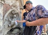 Un hombre se refresca en una fuente en Italia, ante las olas de calor.