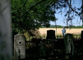 Mirko Bogicevic, de 68 años, residente local y cronista del pueblo, pasa por los cementerios de Kisiljevo el 23 de junio de 2025.over old headstones under a pile of undergrowth. (Photo by OLIVER BUNIC / AFP)