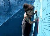 La artista Karina "Kau" Taveras pinta un mural este miércoles, en la Perla en San Juan (Puerto Rico).