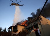Un helicóptero de bomberos y voluntarios luchan para apagar un incendio que quema casas en la zona residencial de Kryoneri, en las afueras de Atenas, Grecia, este sábado 26 de julio.
