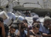 Un niño observa un grupo de palestinos agolpados con sus ollas esperando recibir alimentos de un comedor social en la Franja de Gaza.