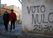 Personas caminan junto a un mural con un mensaje alusivo a la elecciones este sábado, en La Paz (Bolivia).