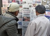 Dos personas leen periódicos con cobertura en portada de las elecciones presidenciales de Bolivia en un quiosco, en La Paz, el 18 de agosto de 2025.