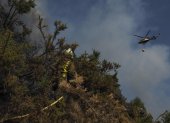 Un helicóptero de la lucha contra el fuego vuela sobre un bombero que trabaja en la extinción del incendio.(Lugo, Galicia).