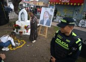 Las mujeres depositan flores junto a un retrato del candidato presidencial asesinado Miguel Uribe en el lugar donde le dispararon el 7 de junio en el barrio Modelia de Bogotá