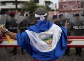 Joven con una bandera de Nicaragua frente a Policías, en Managua (Nicaragua).