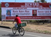 Recompensa. Un hombre observa una valla con el anuncio de recompensa y la imagen del presidente de Venezuela, Nicolás Maduro, y de su ministro de Relaciones Interiores.