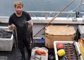 El pescador Chris Kelly, de 32 años, que utiliza redes para sus capturas, posa con un pulpo capturado a bordo de su barco "Shadow", en el suroeste de Inglaterra.