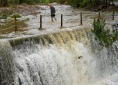 Un hombre cruza un badén inundable durante este lunes en el que el aviso rojo (riesgo extremo). España.