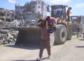 Un hombre con un hatillo con sus pertenencias pasa ante varias excavadoras en la ciudad de Gaza, que comienza este 14 de octubre de 2025 las operaciones de remoción de escombros.