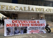 Archivo del 23 de diciembre de 2024 que muestra dos personas sosteniendo un cartel en los exteriores de la Fiscalía Provincial del Guayas.