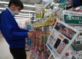 Un empleado clasifica campanillas junto a un anuncio de spray para osos en una tienda de Hanamaki, prefectura de Iwate, el 24 de octubre de 2025.