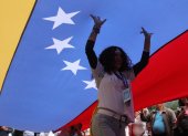Una mujer camina debajo de una bandera durante la marcha "por la paz y la libertad" en Venezuela.