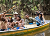 Integrantes de Nat Geo navegan junto a la comunidad Waorani en una embarcación tradicional amazónica.