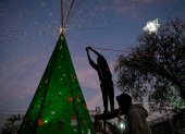 Un hombre decora un árbol de Navidad durante las celebraciones de la Nochebuena en Islamabad el 24 de diciembre de 2025.
