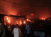 Cuerpo de Bomberos de Honduras trabajan junto a ciudadanos para controlar  un incendio provocado en un puesto de venta de pólvora en San Pedro Sula (Honduras).