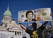 Un partidario del presidente Javier Milei, muestra un cartel de un billete de cien dólares con la imagen del presidente afuera del Congreso.