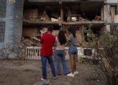 Personas observan un edificio afectado por un explosivo, este 4 de enero de 2026 en Catia La Mar (Venezuela).